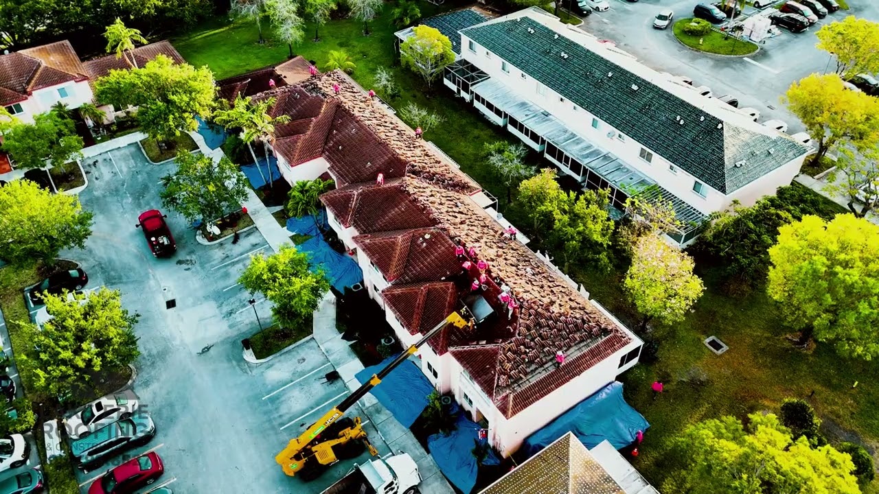 A professional roofing crew wearing bright pink shirts performs a roof installation.